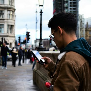 Man on a city sidewalk checking his phone